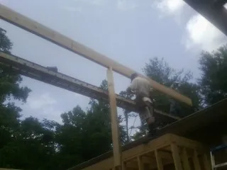 Carpenter setting a ridge beam over a new addition frame — Ice Dam Removal by Roofing Brothers in Wake