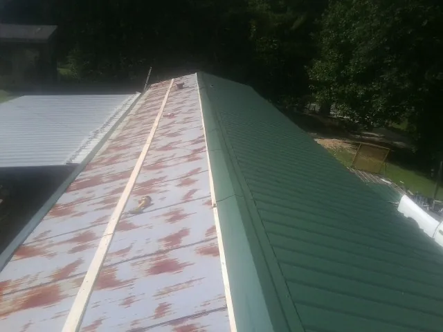 Old rusted panels beside newly installed green metal roofing — Wind Damage Roof Repair by Roofing Brothers in Wake