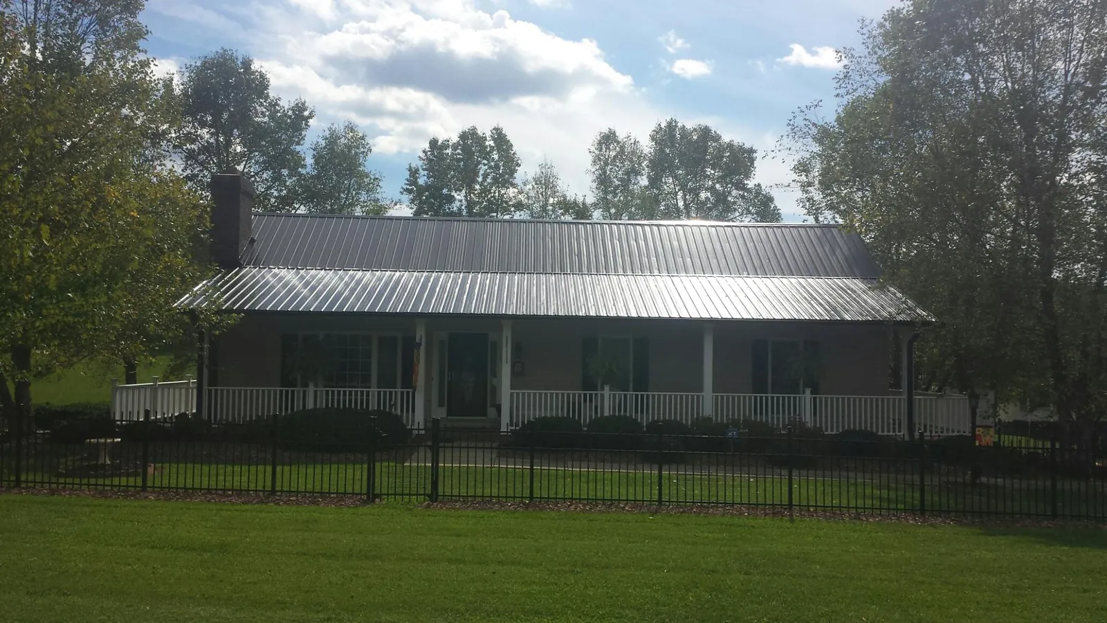 Gray metal roof on a brick ranch with a full width front porch — Gutter Guard Installation work by our crew in Wake