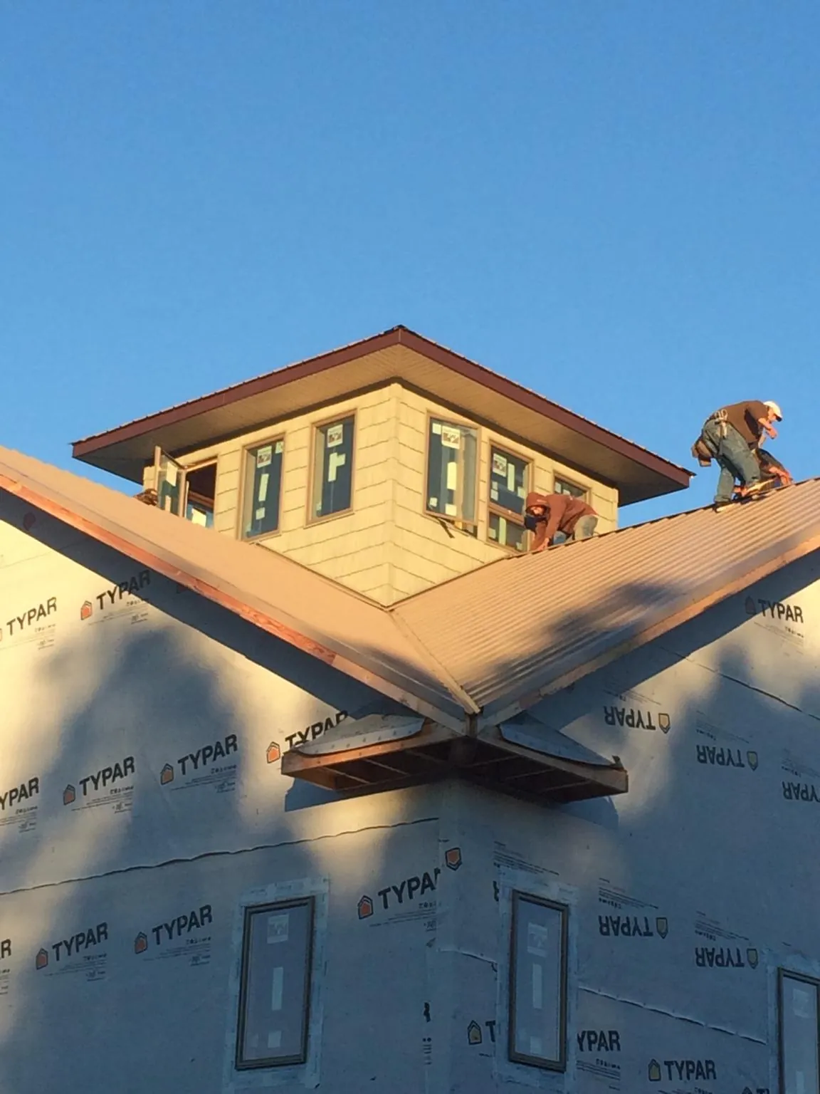 Roofers working around a rooftop cupola on a new metal roof at sunset — Roof Waterproofing in Wake by Roofing Brothers
